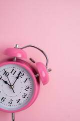 Pink alarm clock isolated on a vibrant pink background for time management and pink october concept