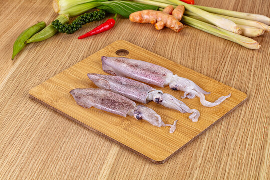 Raw squid on cutting board with fresh Asian spices and vegetables