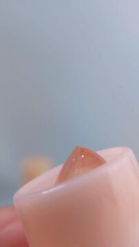 Pink lip balm slowly coming out and twisting from product packaging. Close up view, soft glossy texture for lip care beauty concept.