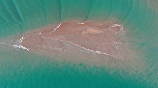 Aerial view of a secluded, pristine sandbar surrounded by tranquil turquoise waters in the Whangamata, Coromandel Peninsula, New Zealand, showcasing the natural beauty of the ocean.