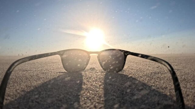 Relaxing beach composition with sunglasses on Kijkduin Beach during a windy sunset and distant kiteboarding