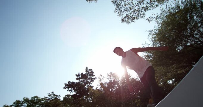 Experience the freedom of movement in 1000fps slow motion. Young man leaps through the air with arms outstretched like wings, embodying the spirit of Yamakasi in Bangkok park. Concept freedom flight
