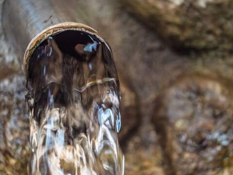 Close up of clean fresh natural water flowing from a metal pipe in a mountain spring, ecology and environment concept