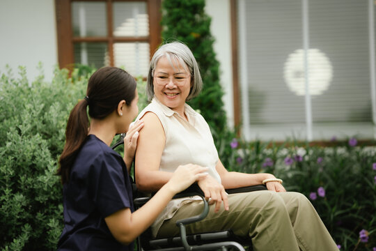 Professional caregiver assisting a senior woman in a wheelchair outdoors, promoting mobility, independence, and compassionate elderly care.