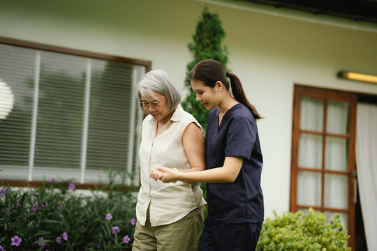 Professional caregiver assisting a senior woman during an outdoor walk, promoting mobility, balance, confidence, and independent aging.