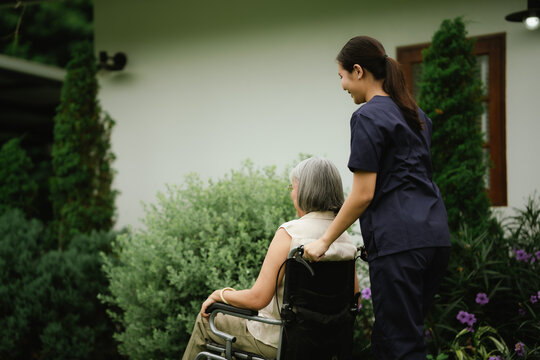 Professional caregiver assisting a senior woman in a wheelchair outdoors, promoting mobility, independence, and compassionate elderly care.