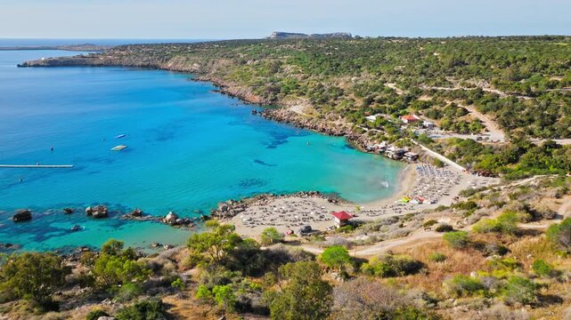 Drone view of Konnos Bay near Protaras, Cyprus. Curved coastline, turquoise sea and natural greenery shape a relaxing beach panorama.