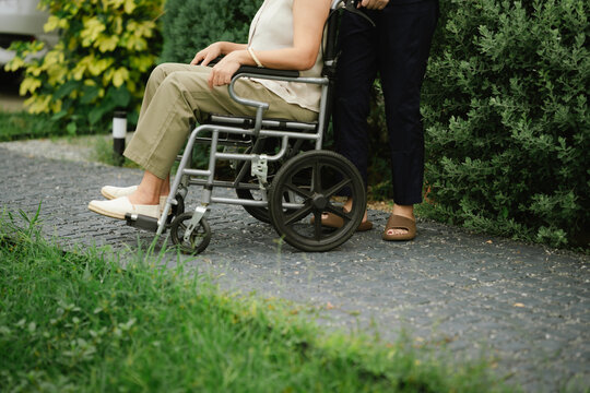 Professional caregiver assisting a senior woman in a wheelchair outdoors, promoting mobility, independence, and compassionate elderly care.