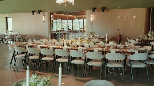 Long banquet table with chairs flowers and candles inside reception hall