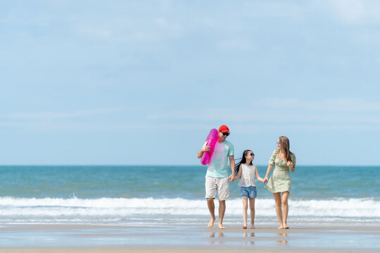 A cheerful family enjoys a peaceful beach vacation surrounded by blue skies and ocean waves representing love relaxation and meaningful family moments.