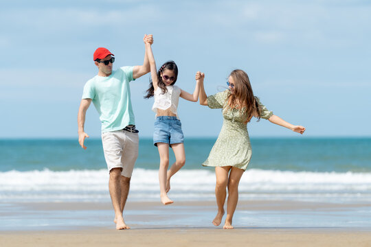 Joyful parents lifting their daughter while enjoying a relaxing beach vacation celebrating family love happiness and unforgettable summer moments.

