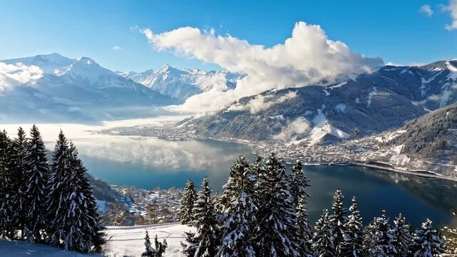 Stunning aerial winter panorama of alpine lake Zell am See with snow capped mountains and evergreen forests.