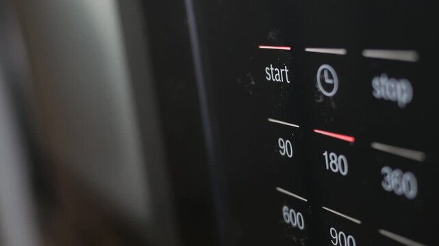 A close up shot of person pressing the start button of a kitchen microwave oven