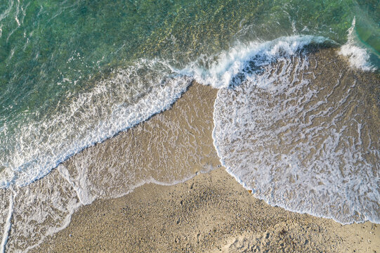 Relaxing aerial beach view with calm sea water and stone, slabs, lump, coral. Summer vacation. Blue ocean lagoon, sea shore, coastline. Drone, copter top view.