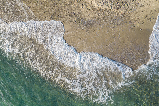 Relaxing aerial beach view with calm sea water and stone, slabs, lump, coral. Summer vacation. Blue ocean lagoon, sea shore, coastline. Drone, copter top view.