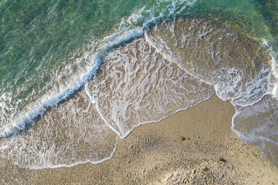 Relaxing aerial beach view with calm sea water and stone, slabs, lump, coral. Summer vacation. Blue ocean lagoon, sea shore, coastline. Drone, copter top view.