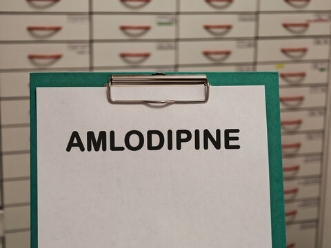 AMLODIPINE calcium channel blocker for hypertension and angina displayed on a clipboard in a pharmacy