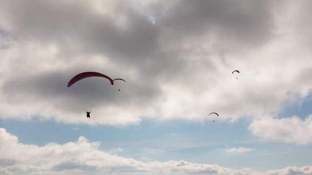 Paragliding adventure sport against bright sun on cloudy sky