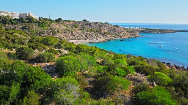 Aerial view of Konnos Bay near Cavo Greco, Cyprus. Green coastal forest, rocky cliffs and turquoise Mediterranean water create a peaceful summer landscape.