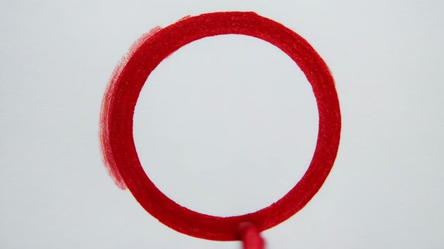 Hand drawing red circle with marker on white paper in cinematic motion during creative process
