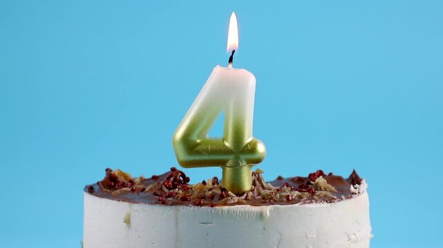 Number 4 birthday candle burning on cake. The fourth birthday or anniversary celebration concept. Lot of copy space on blue background.