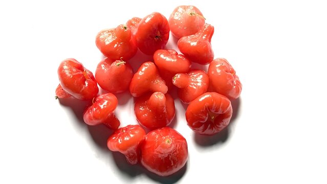 Many fresh red rose apples scattered on a white surface