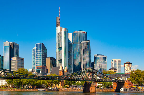 Frankfurt, Germany - May 15, 2026: Scenic financial district skyscrapers skyline with Commerzbank Tower rising behind Eiserner Steg iron bridge