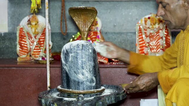 Hindu Worshippers Bhasma (holy ash) offerings to Holy Shiva Lingam During Devotional Temple Ritual