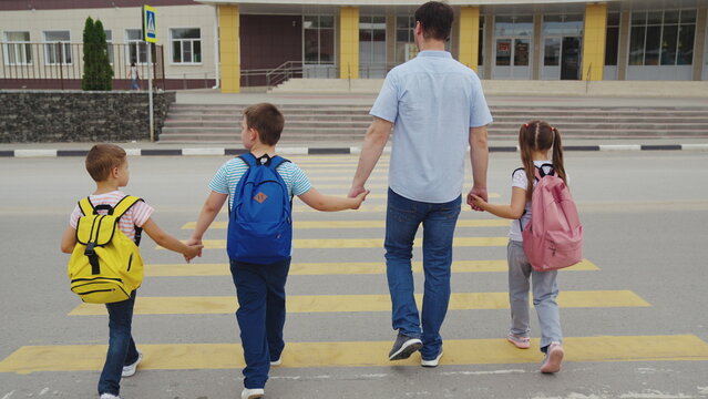 Father leads kids to class, Learning togetherness, Community education, Safe passage to school, Urban family life, Everyday school ritual, Children excited to learn, Supportive family ties, Morning