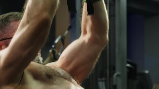 Man performs close grip cable row during focused gym session. Athlete pulls parallel handles toward torso controling resistance through movement