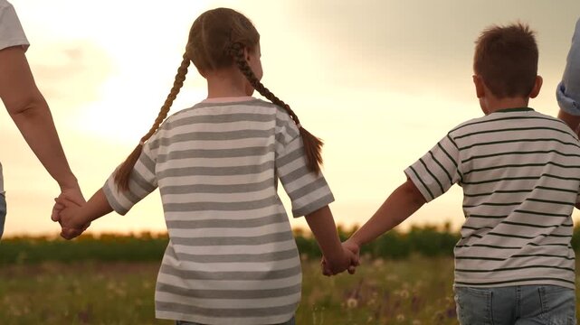 Family girl boy mother father walking field sunset, Happy family outdoors, Parents children girl boy mother father together nature, Family time countryside, Four people holding hands, Rear view family
