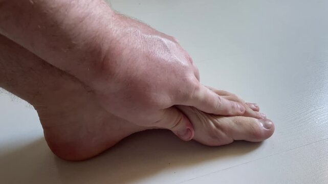Man Massaging Painful Foot Heel and Arch Close Up