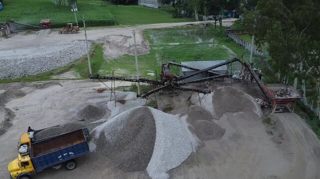 Industrial gravel processing plant with conveyor belts and large stone piles near a rural road industry mine truck sand aggregate industry mine truck sand aggregate