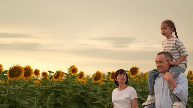 Family walk in sunflower field, Happy family in nature, Father carrying daughter on shoulders, Mother holding hands with family, Sunset family portrait, Smiling child in sunflower field, Summer