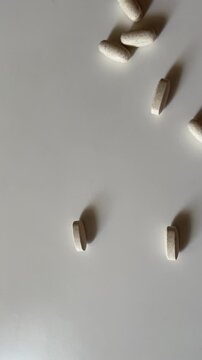 Pills and Supplements Falling onto White Table Surface in Slow Motion