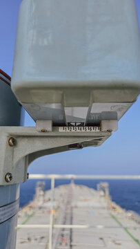 Close up view of navigational equipment repeater on bridge wing of oil tanker ship with vessel bow and open sea background during sunny navigation day