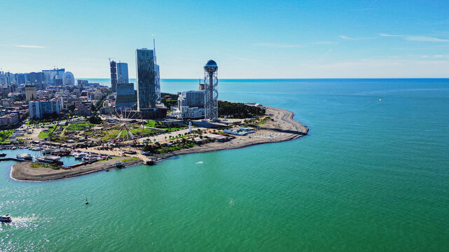 Aerial view of Batumi resort city coast with Alphabet Tower and ferris wheel on Black Sea shore in Georgia during sunny summer day with clear blue sky landscape