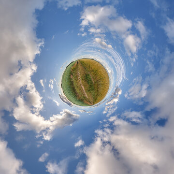 simple little tiny planet without buildings in blue sky with sun and beautiful clouds. Transformation of spherical panorama 360 degrees. Spherical abstract aerial view. Curvature of space.