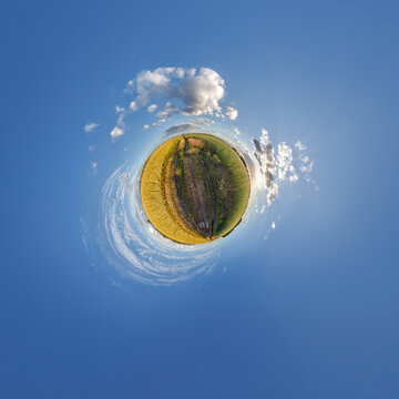 simple little tiny planet without buildings in blue sky with sun and beautiful clouds. Transformation of spherical panorama 360 degrees. Spherical abstract aerial view. Curvature of space.