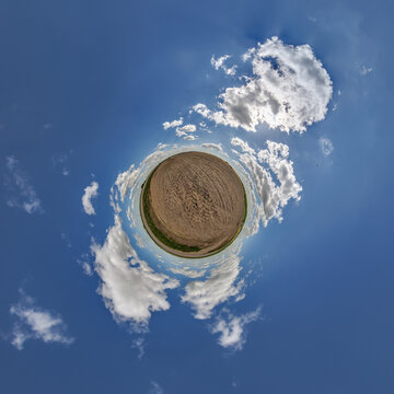 simple little tiny planet without buildings in blue sky with sun and beautiful clouds. Transformation of spherical panorama 360 degrees. Spherical abstract aerial view. Curvature of space.