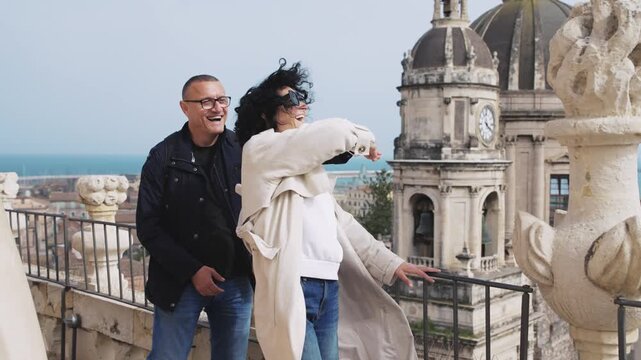 Joyful couple dancing on rooftop overlooking Catania cityscape