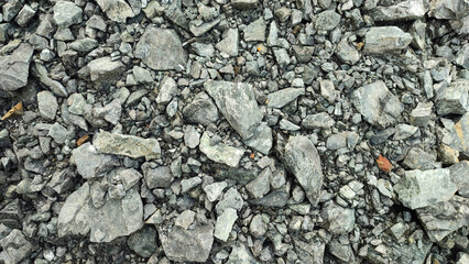 Close-up texture of sharp crushed grey stones, slate, and mineral rock fragments. A detailed natural background for building, geology, and 3D textures. © Munif Rifa'i