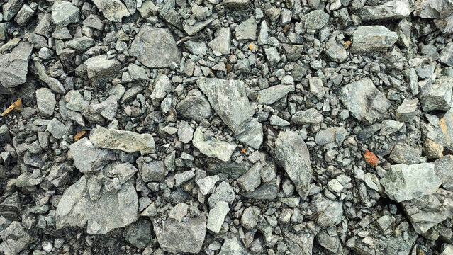 Close-up texture of sharp crushed grey stones, slate, and mineral rock fragments. A detailed natural background for building, geology, and 3D textures.