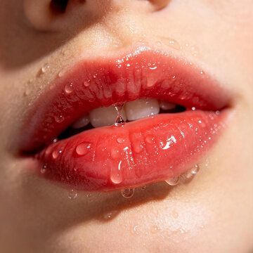Extreme macro of hydrated female lips with pink lipstick and clear water droplets, showcasing moist skin and bright lighting for beauty concepts.