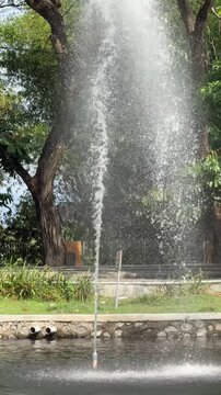 High vertical water fountain jet spraying in a public park pond