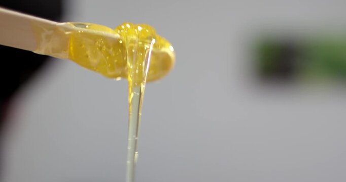 Golden sugaring paste on wooden spatula for hair removal