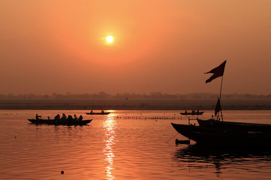 Silhouettes of passengers aboard wooden boats at sunrise on the Ganges River in Varanasi, India