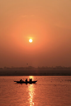 Silhouettes of passengers aboard wooden boats at sunrise on the Ganges River in Varanasi, India
