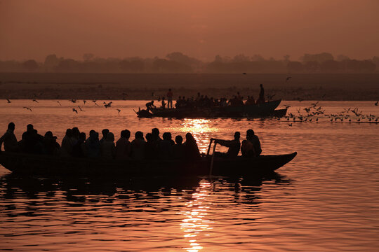 Silhouettes of passengers aboard wooden boats at sunrise on the Ganges River in Varanasi, India