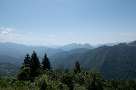 Panoramic mountain ridges and forests of Val Palot under a clear blue summer sky in Lombardy northern Italy landscape